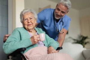 An elderly person with a cane walking slowly down a brightly lit hallway with color-contrasting handrails.
