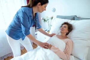 Older adult reviewing a care plan with a caregiver at a table with medications and a blood pressure monitor.