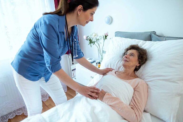 Older adult reviewing a care plan with a caregiver at a table with medications and a blood pressure monitor.
